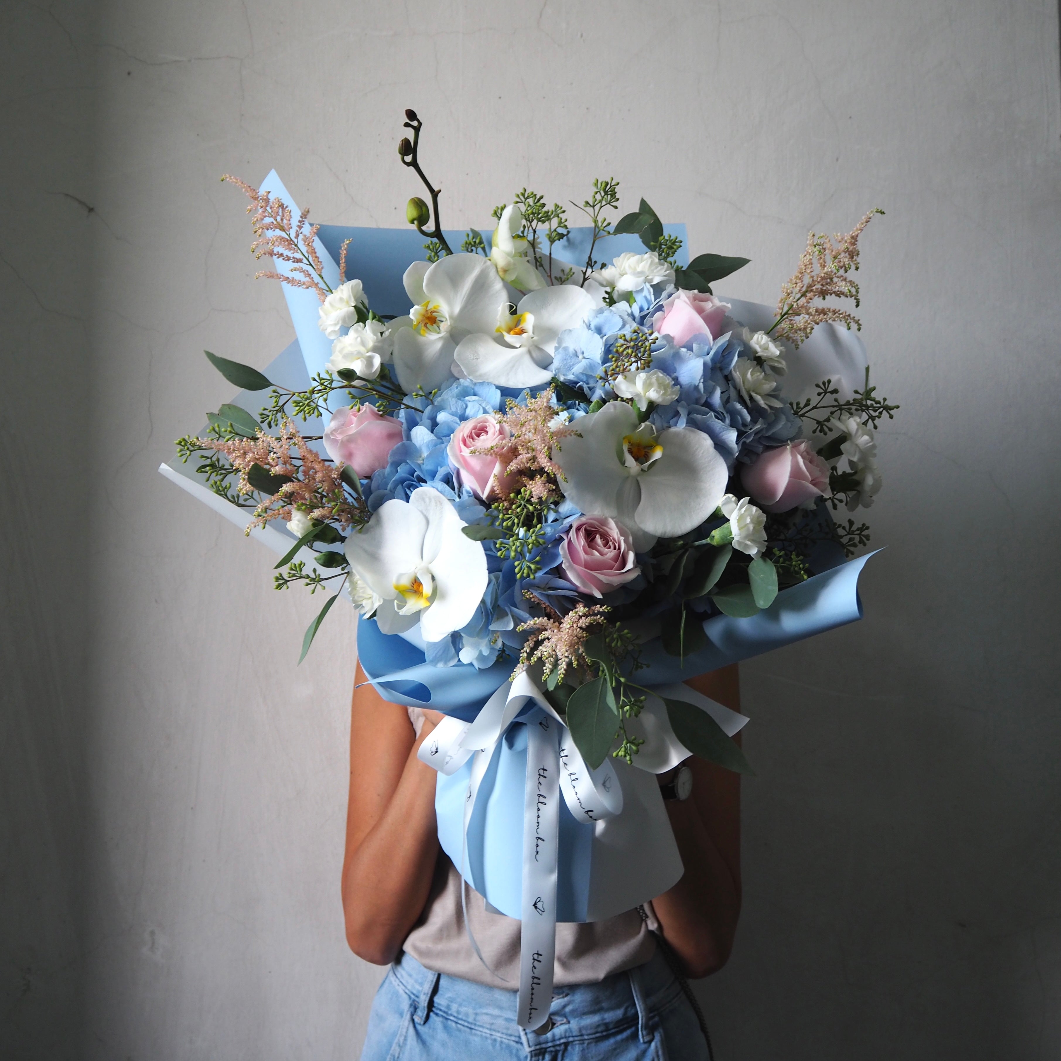 Bouquet of flowers held by a person against a plain background