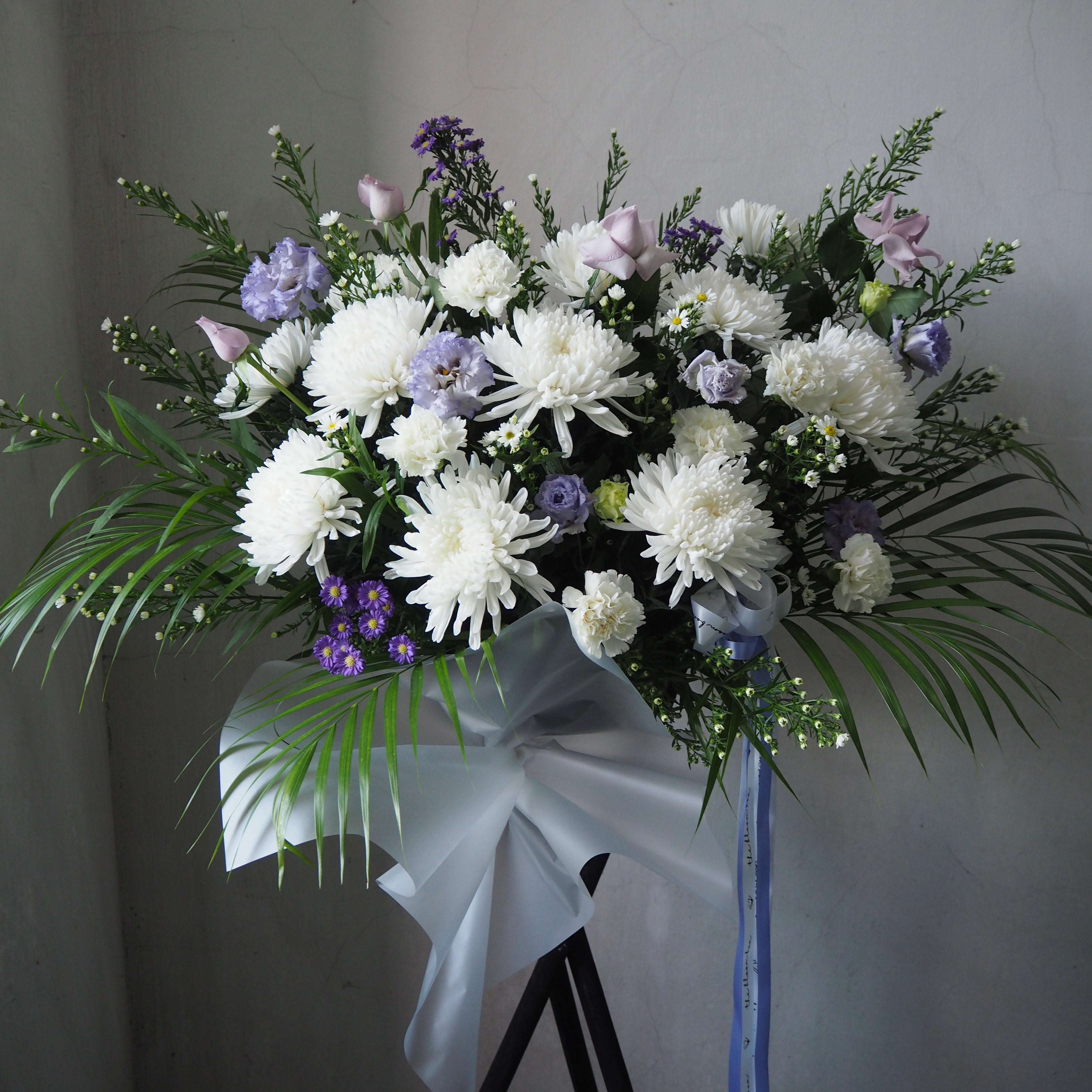 Bouquet of white and purple flowers with greenery on a gray background