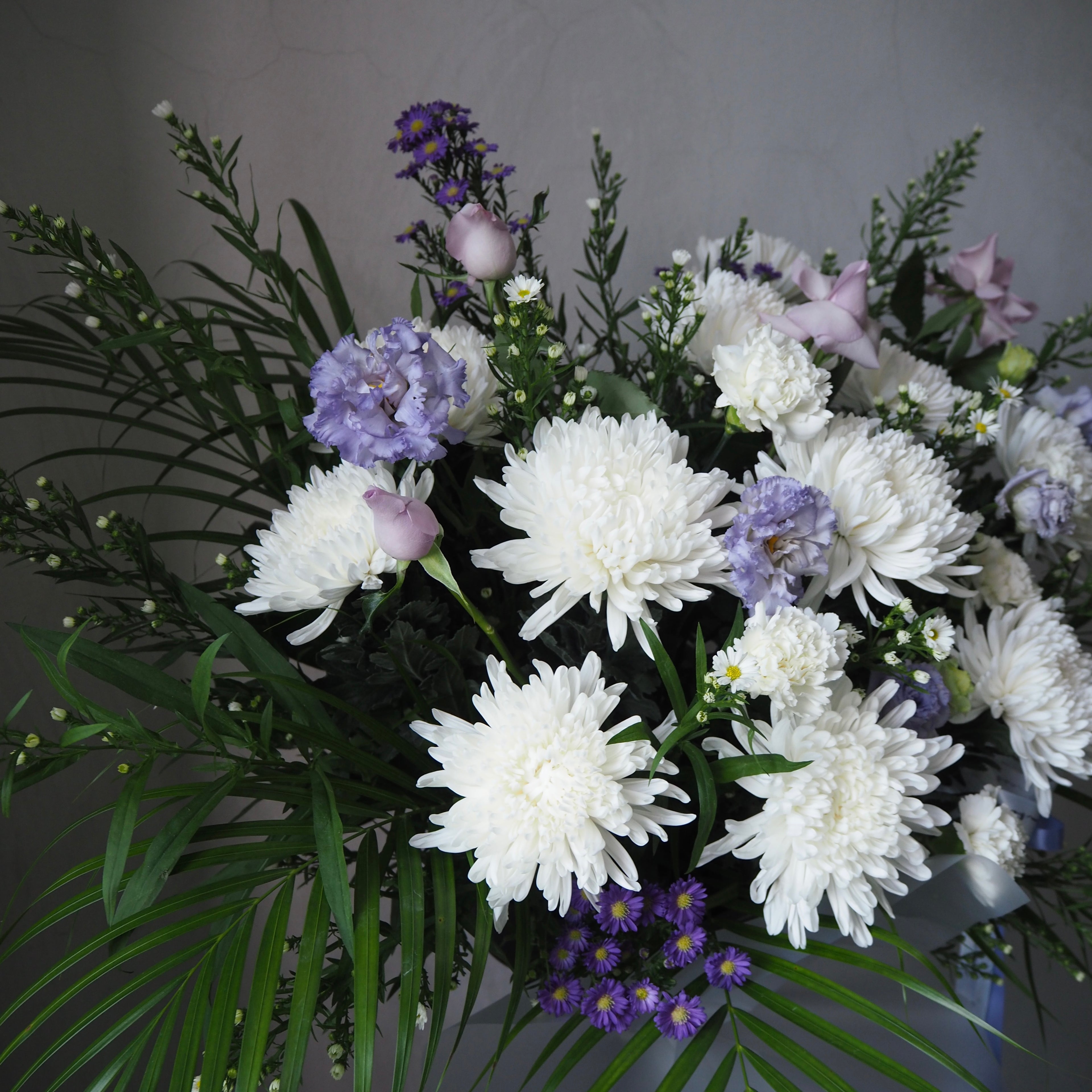 Bouquet of white and purple flowers with green leaves on a gray background