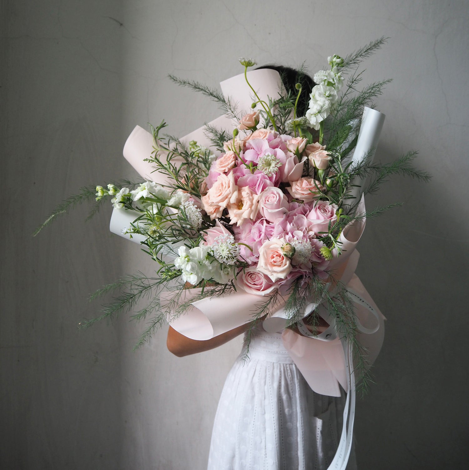 Person holding a large bouquet of flowers against a plain background