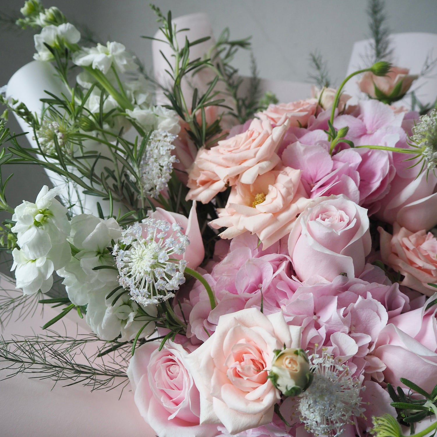 Bouquet of pink and white flowers with greenery on a light background