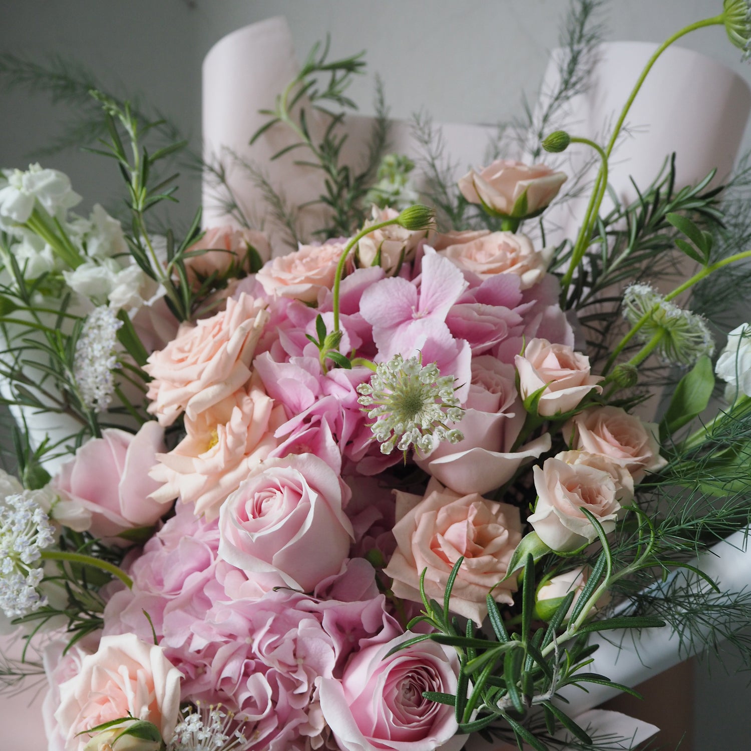 Bouquet of pink and white flowers with greenery on a neutral background