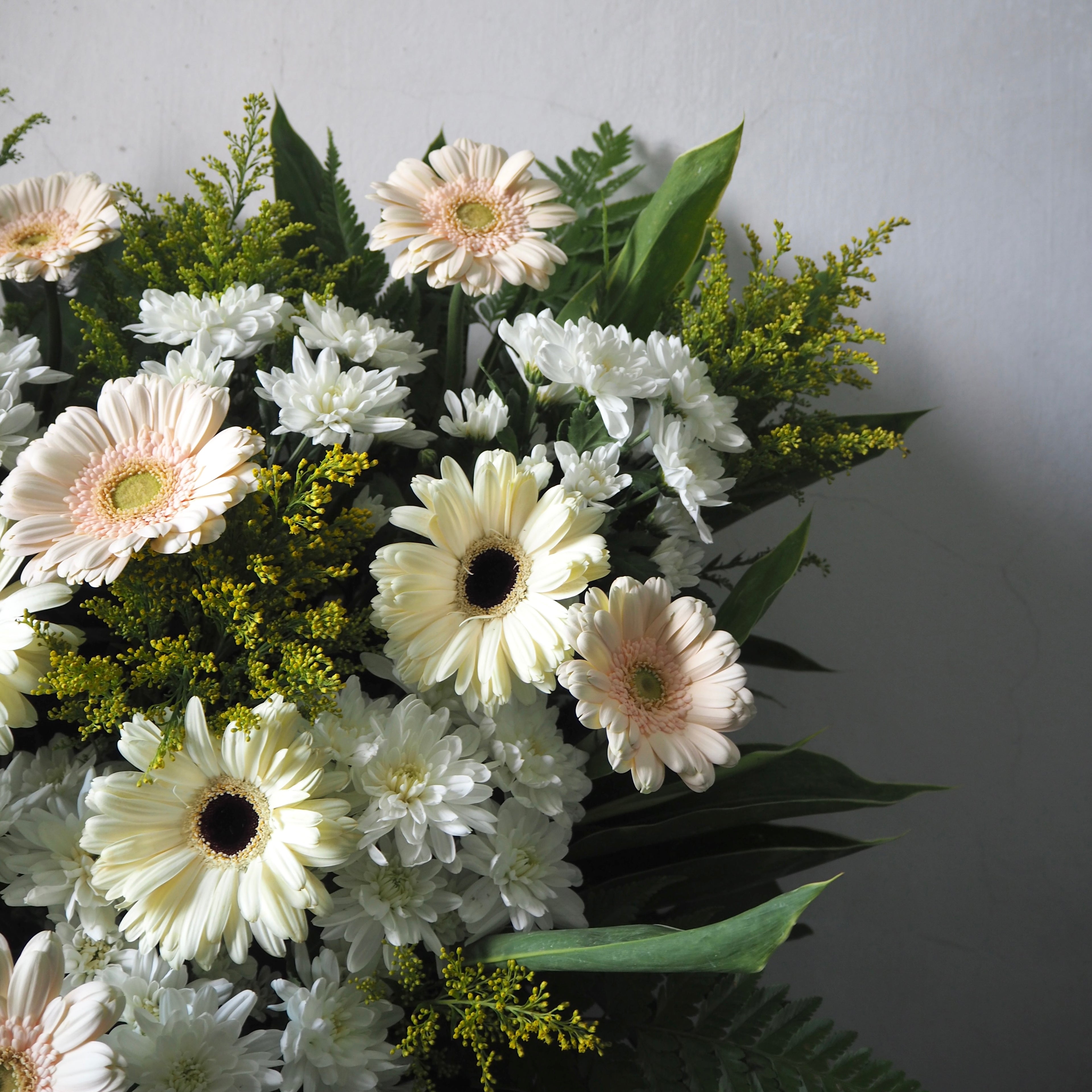 Bouquet of white and pink flowers with green leaves on a light gray background