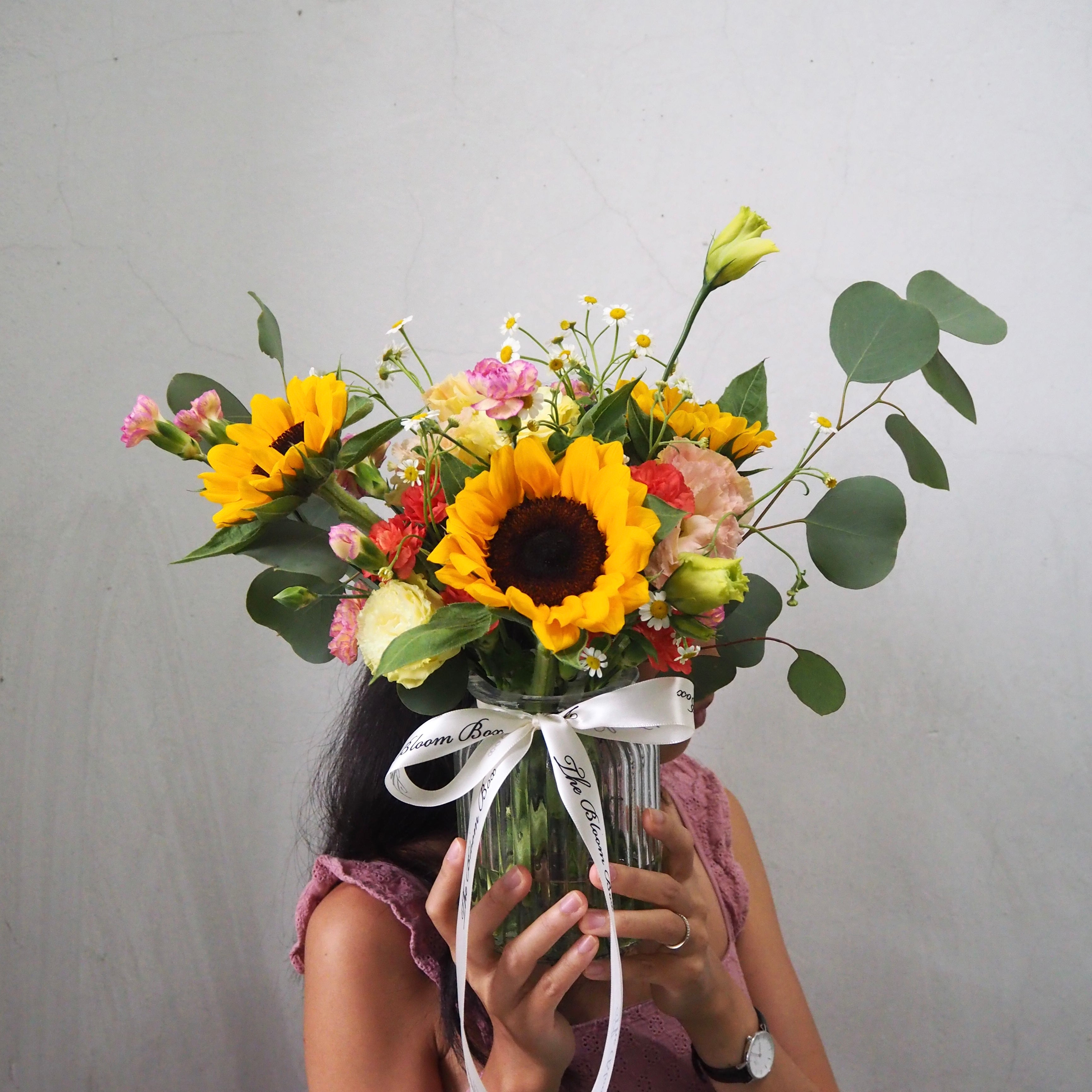lady holding sunflowers arrangement in transparent vase