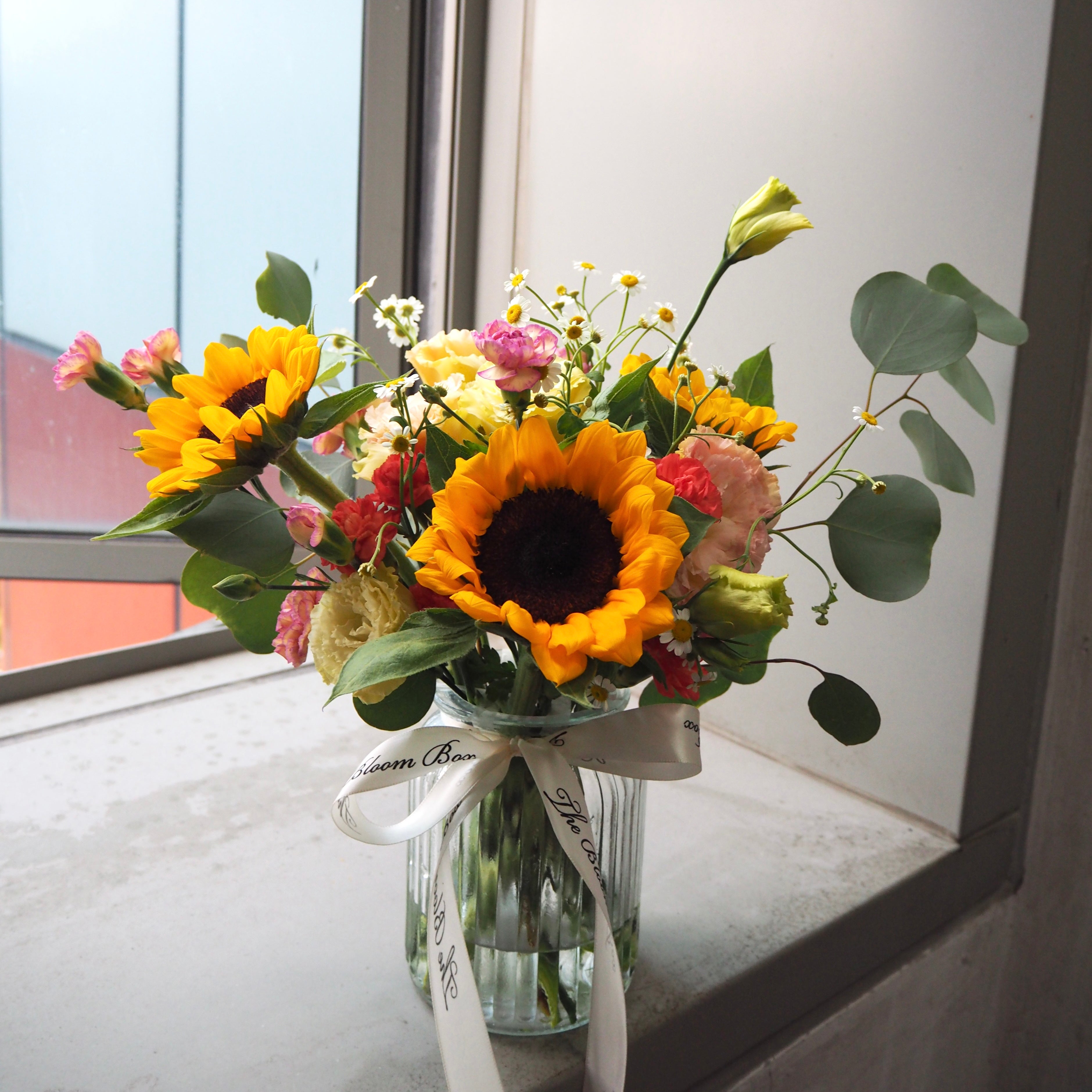 sunflowers arrangement in transparent vase by window