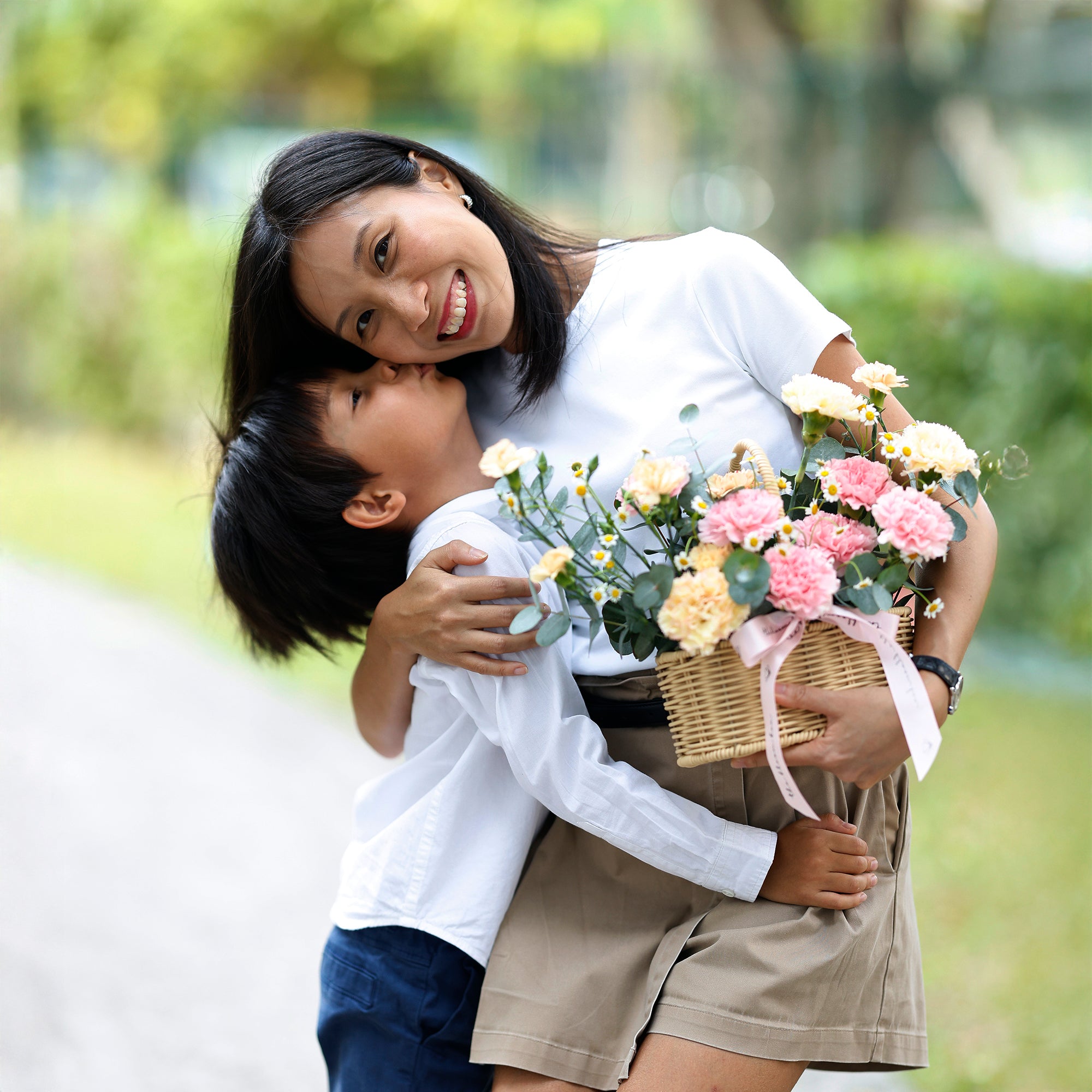 Woman holding a child and a basket of flowers in a park setting