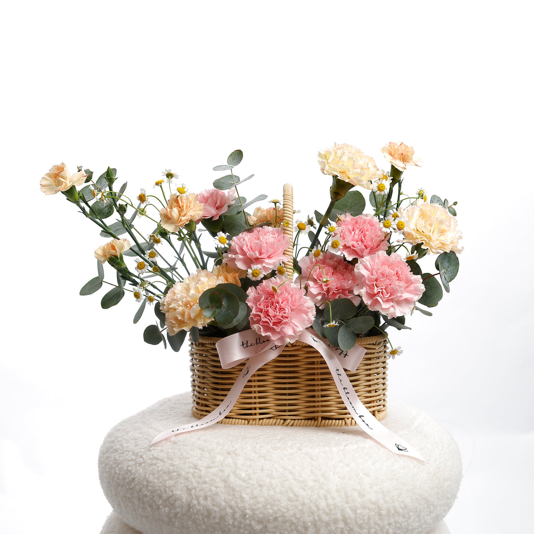 Wicker basket with pink and white flowers on a white background