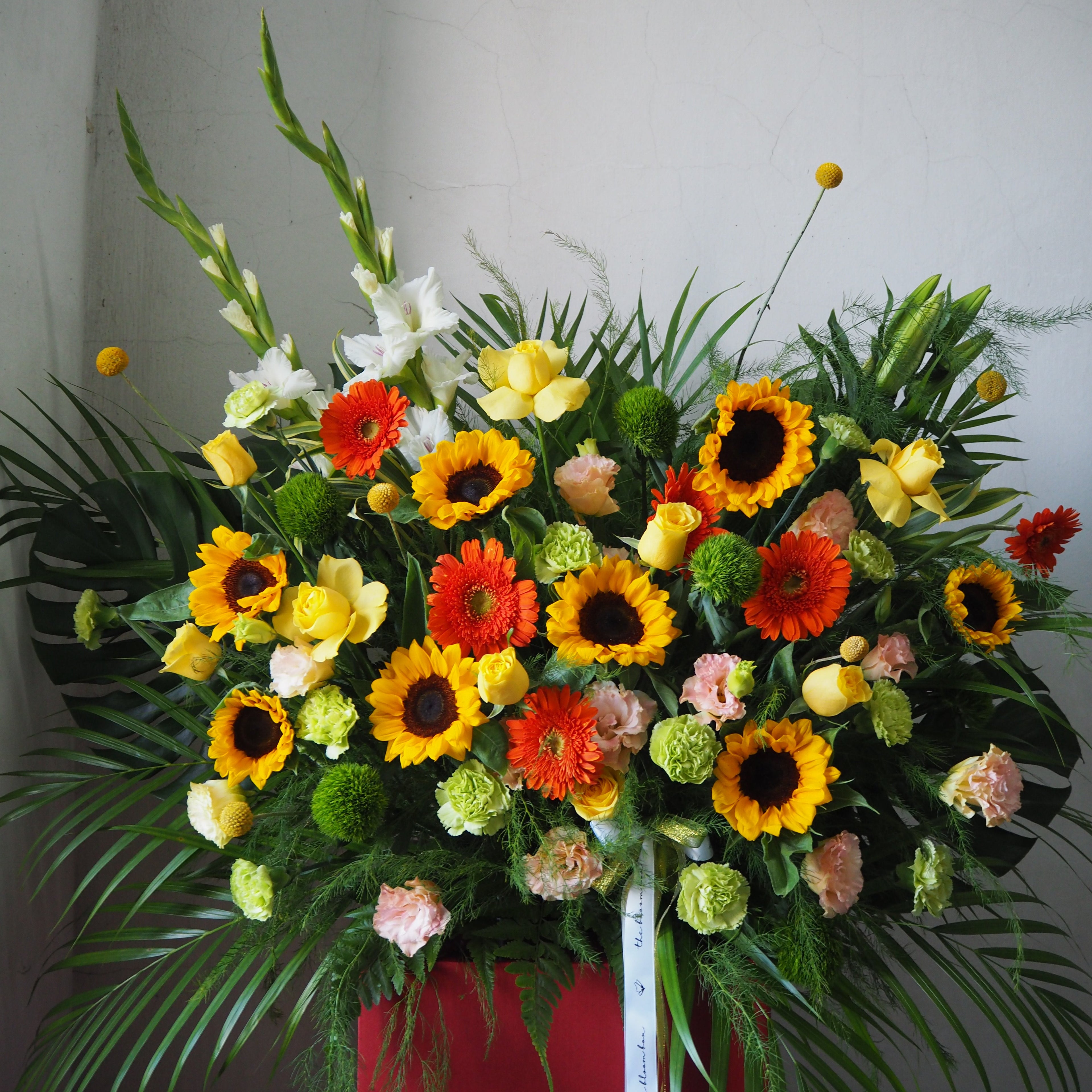 Colorful flower arrangement with sunflowers, roses, and other flowers on a plain background