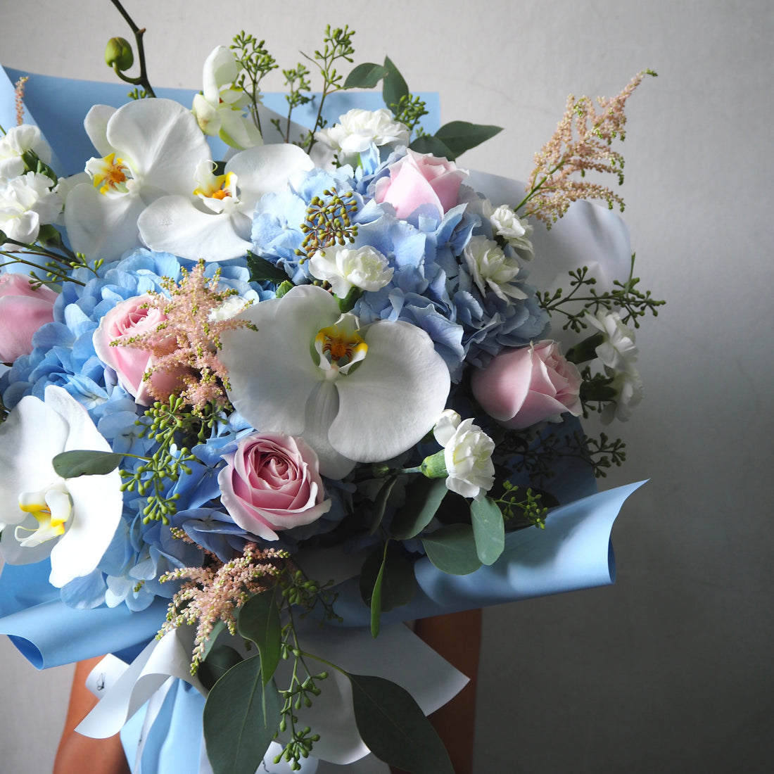 Bouquet of flowers with blue, pink, and white colors on a plain background