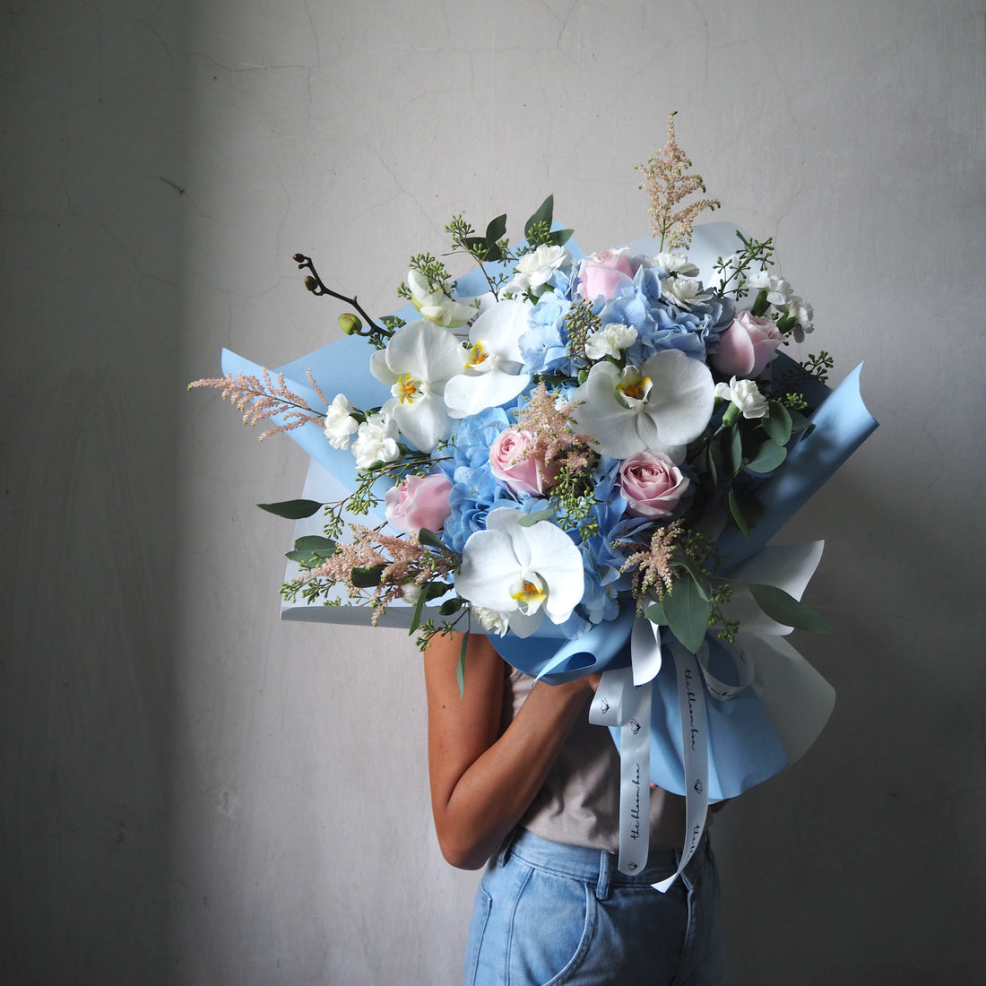 Person holding a bouquet of flowers against a plain background