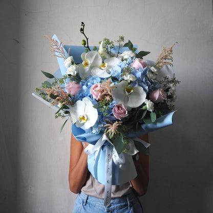 Bouquet of flowers held by a person against a plain background