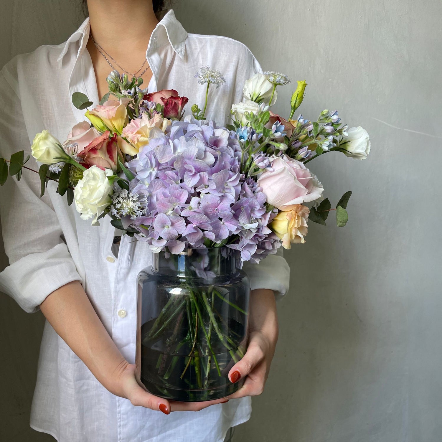 hydrangea and mixed colour roses flower arrangement in a black vase