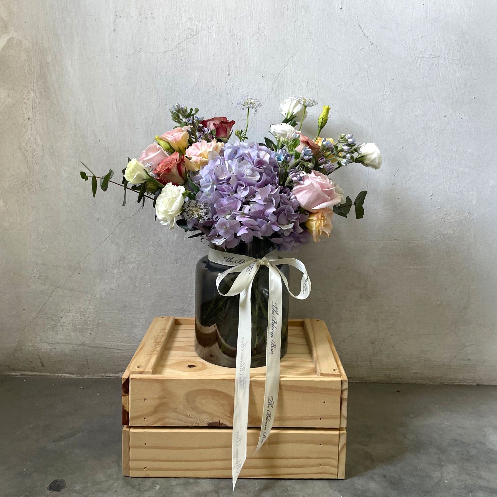 hydrangea and mixed colour roses flower arrangement in a black vase