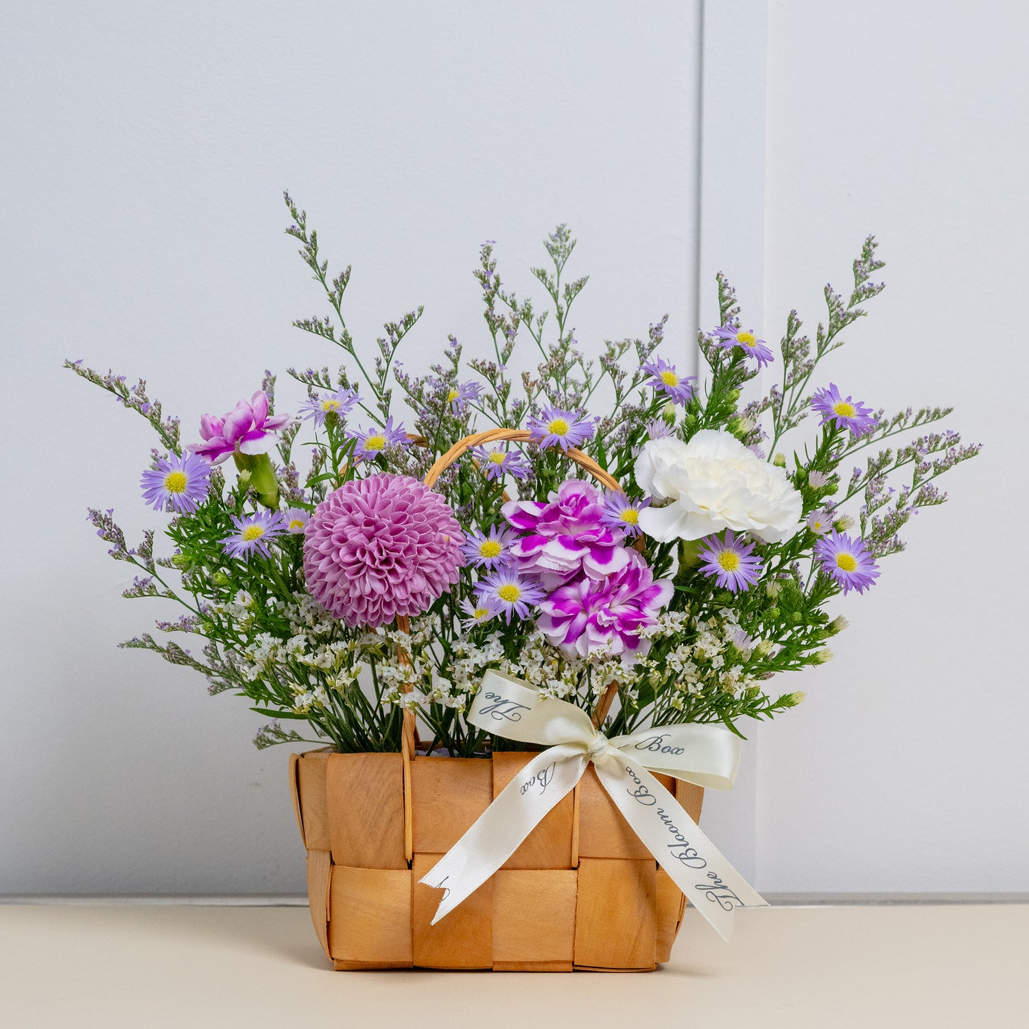 front view of purple flower arrangements in small petite basket