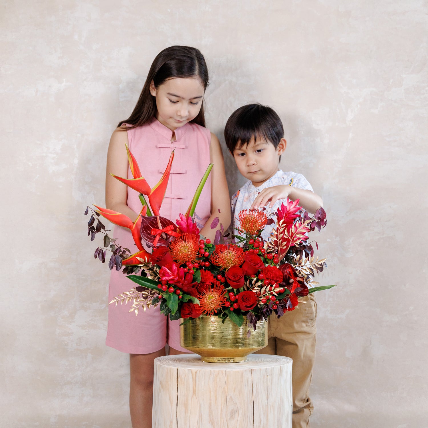 Two children with a vibrant floral arrangement on a light background