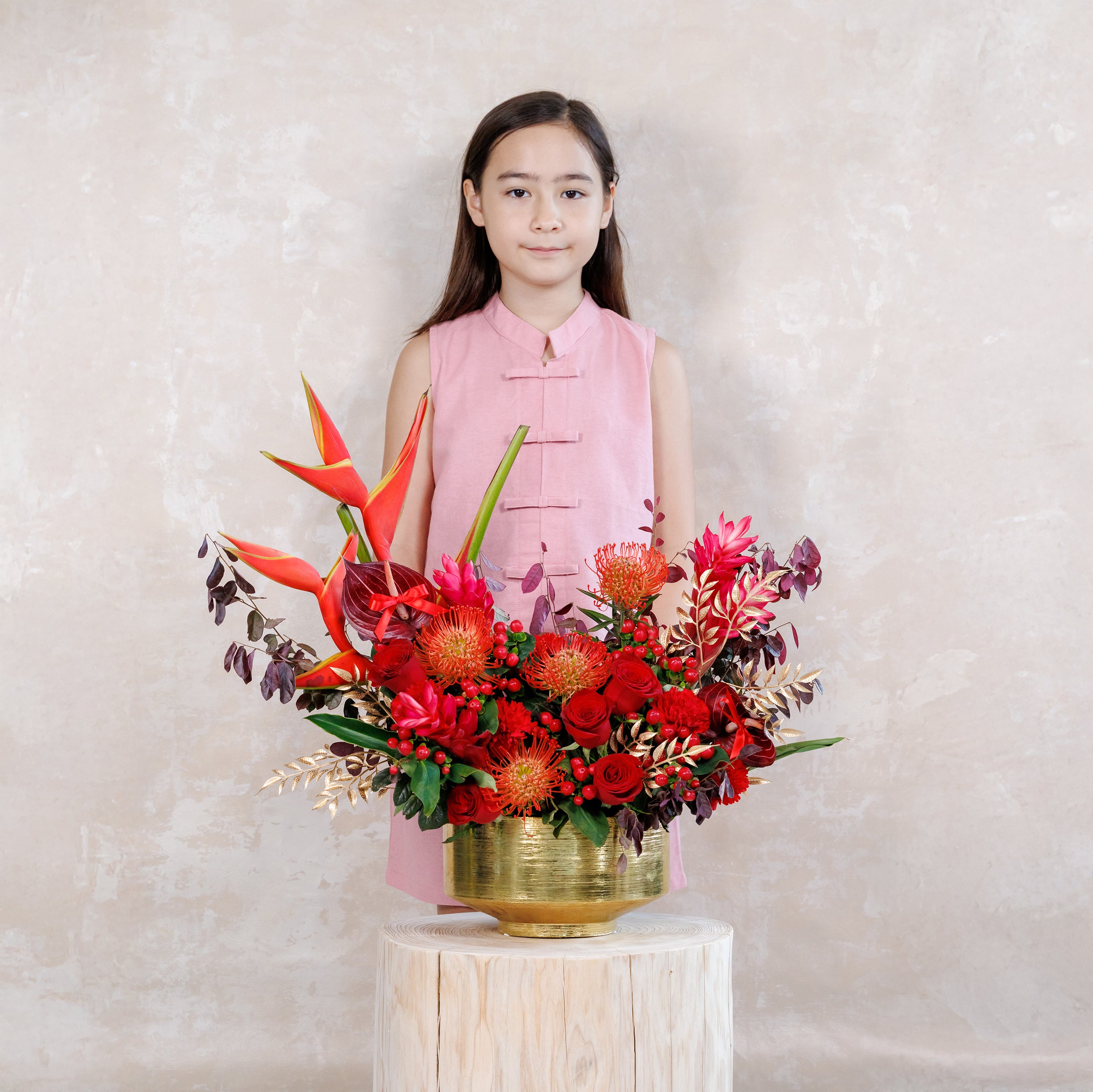 Young girl standing behind a large bouquet of red and pink flowers on a white background