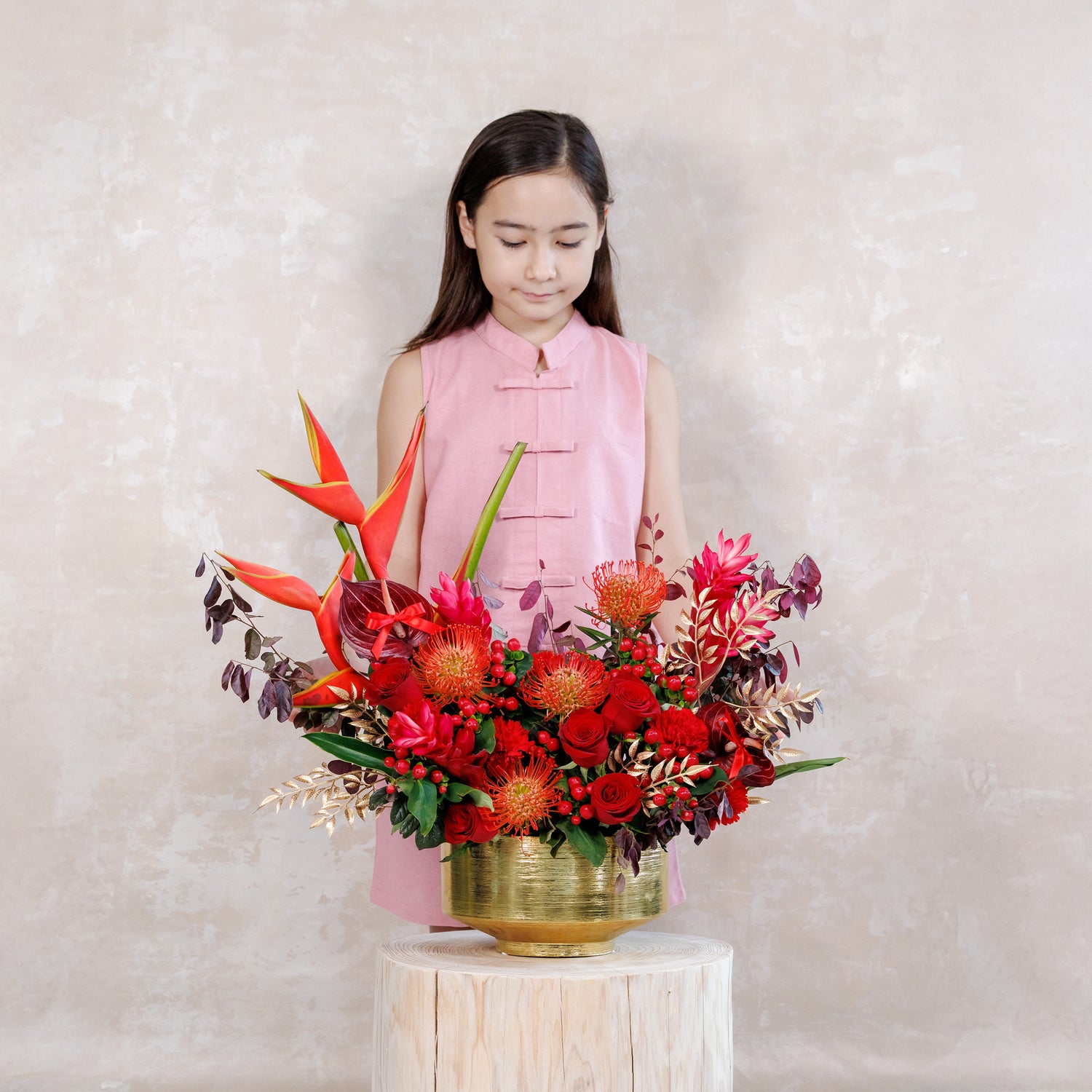 Girl holding a vibrant floral arrangement against a plain background