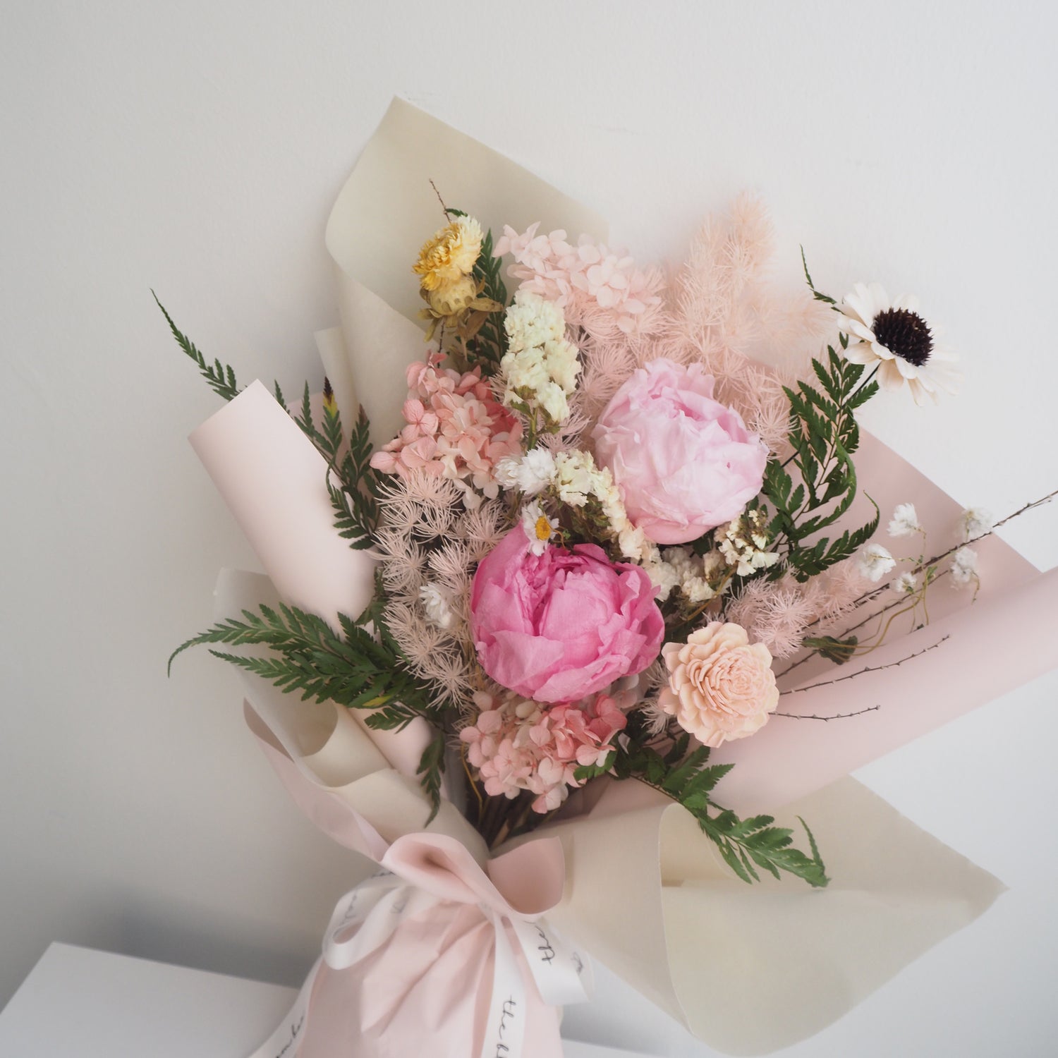 Bouquet of pink and white flowers with green leaves on a light background