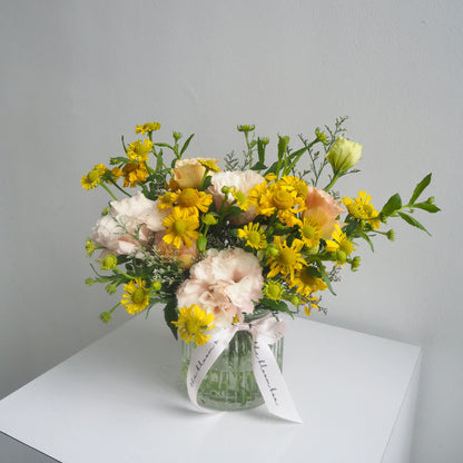 Bouquet of flowers in a clear vase on a white surface with a gray background