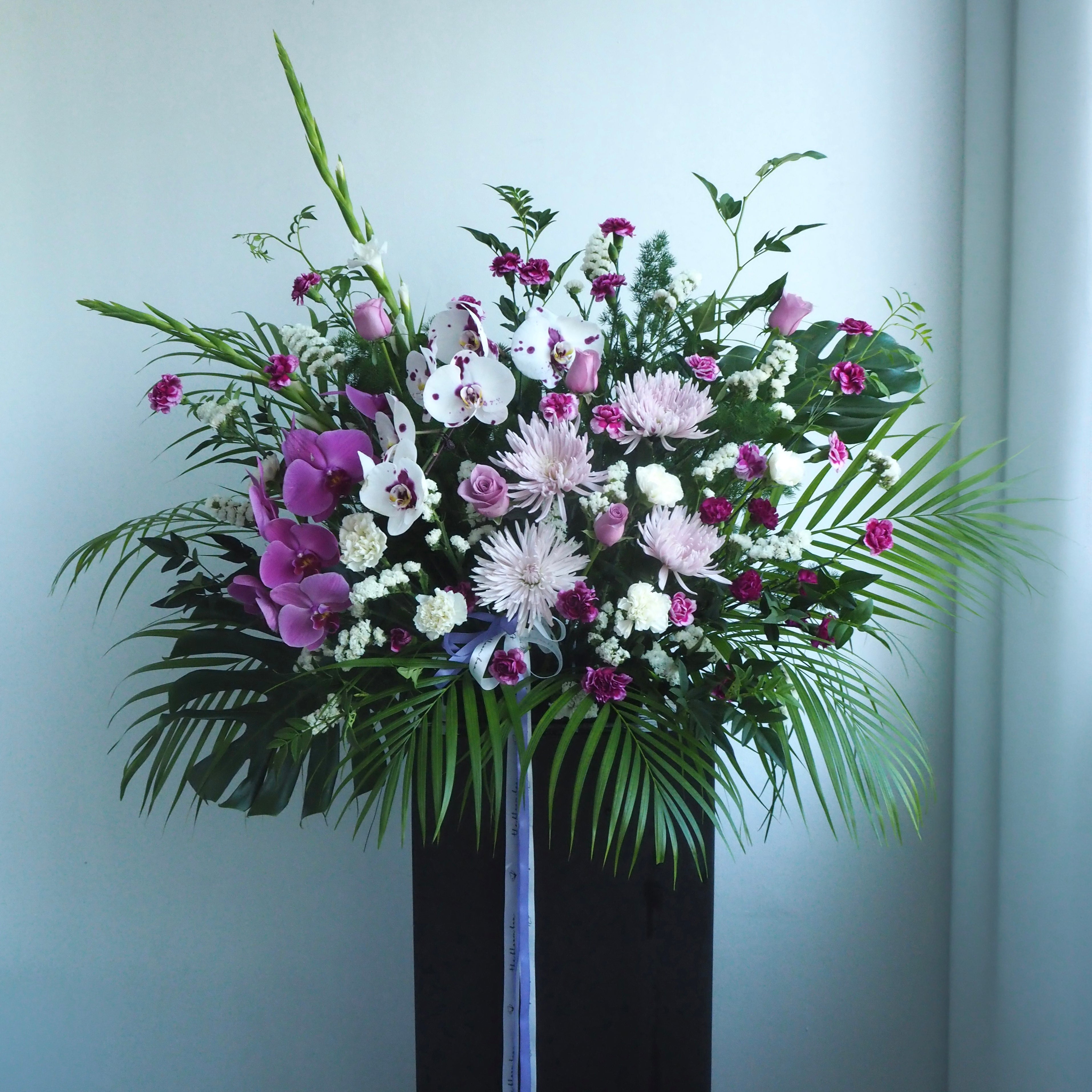 Iris condolence flower stand with white-purple phalaenopsis orchids and muted purple tones