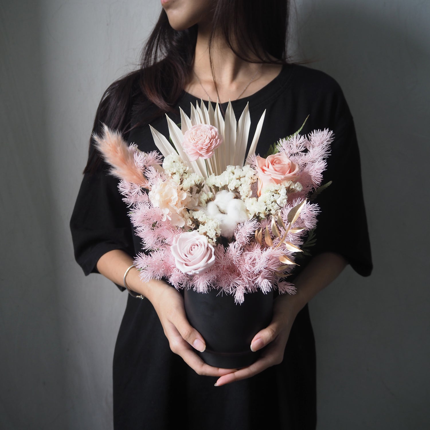 lady holding black vase with pink tones preserved flowers