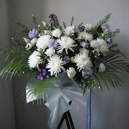 Bouquet of white and purple flowers with greenery on a gray background