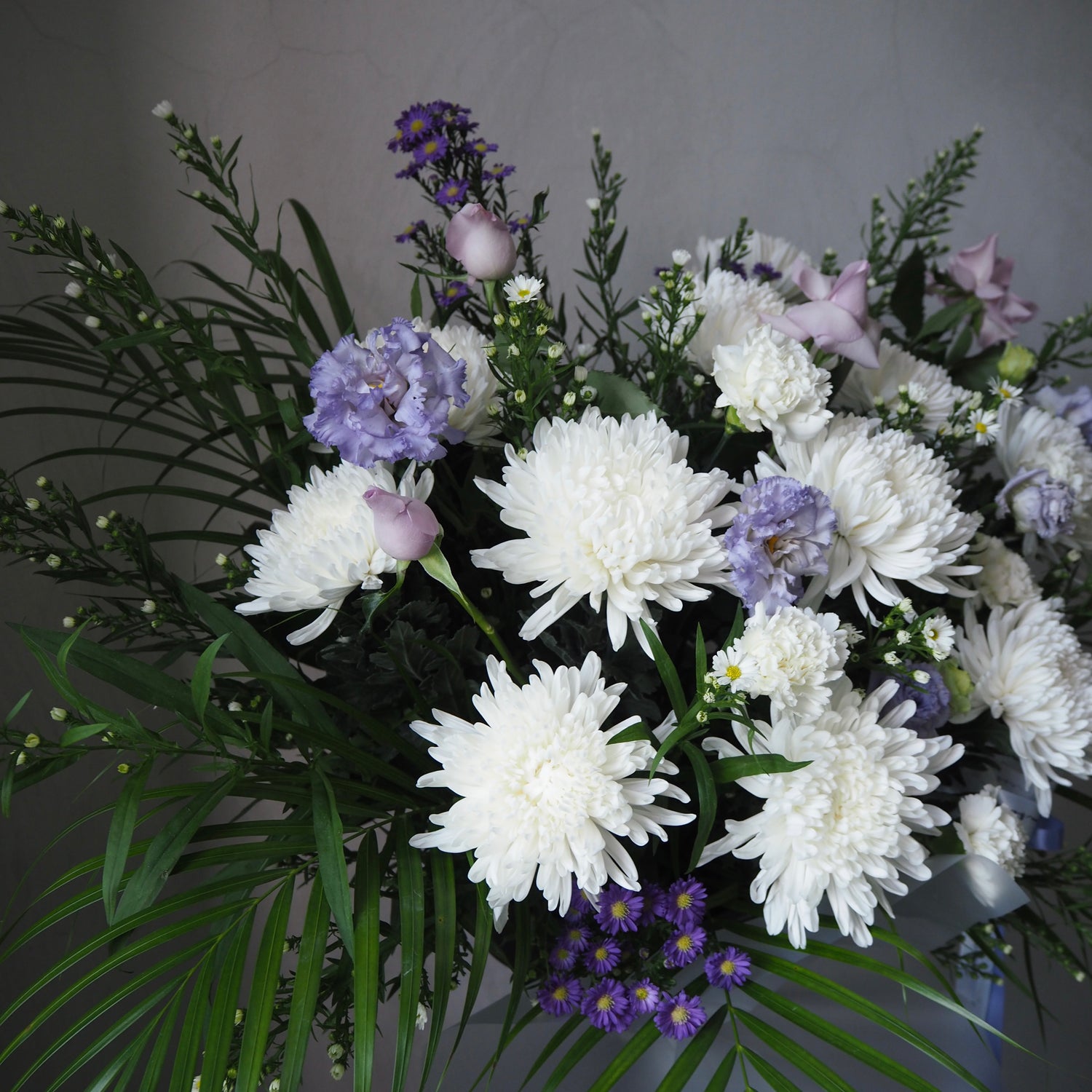 Bouquet of white and purple flowers with green leaves on a gray background