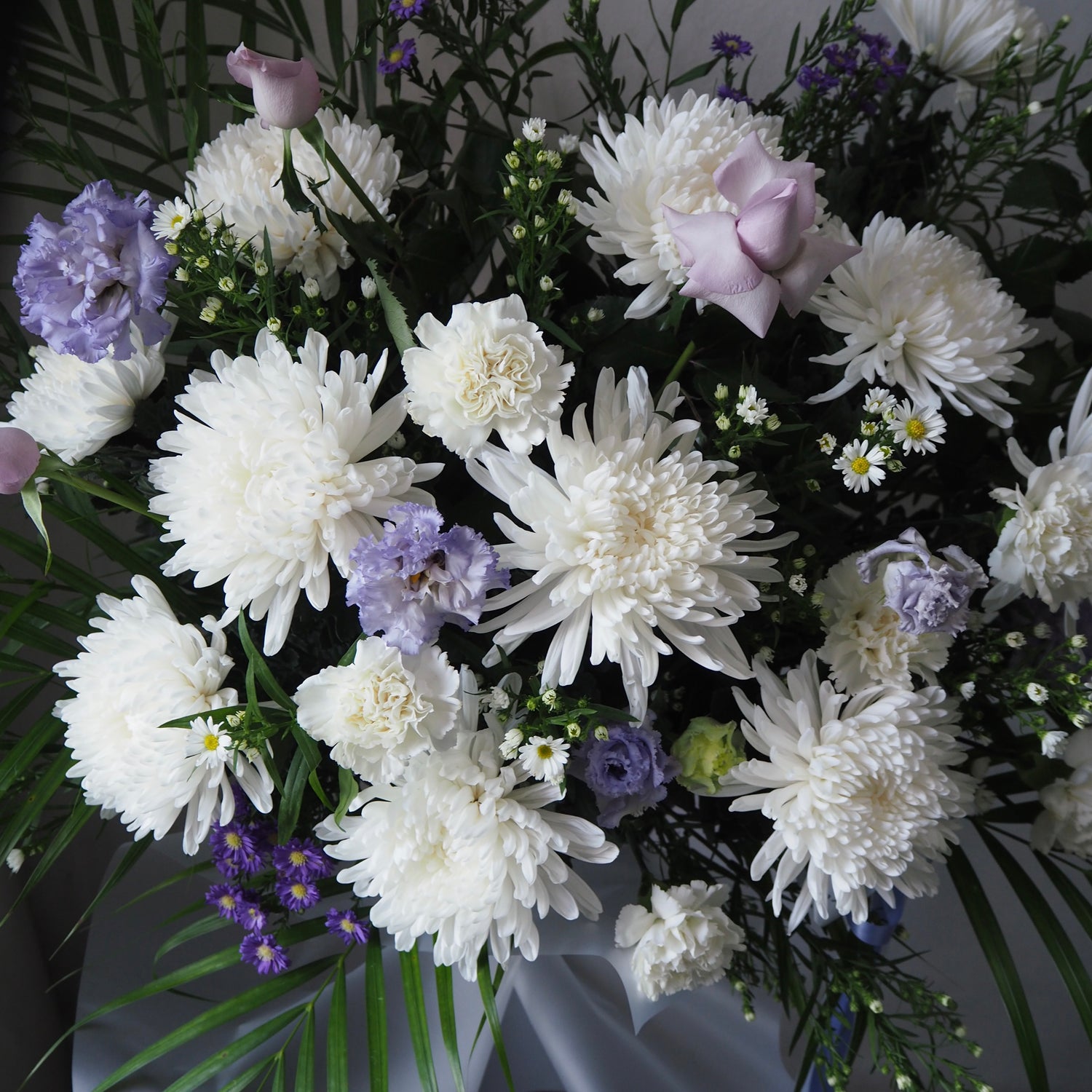 Bouquet of white and purple flowers with greenery on a dark background