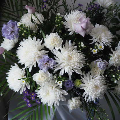 Bouquet of white and purple flowers with greenery on a dark background