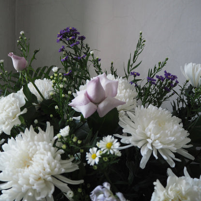 Bouquet of white and purple flowers against a neutral background