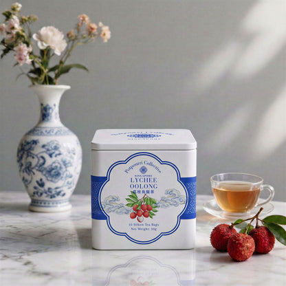 Tea canister with lychee oolong label on a marble surface with a cup of tea, lychees, and a vase in the background for Mother&
