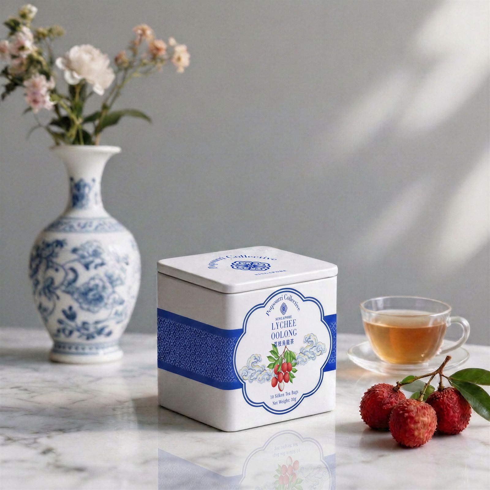 Potpourri Collective Tea tin with floral design, cup of tea, and lychees on a marble surface for Mother&