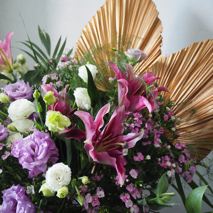 Bouquet of flowers with pink, purple, and white flowers against a gold leaf background