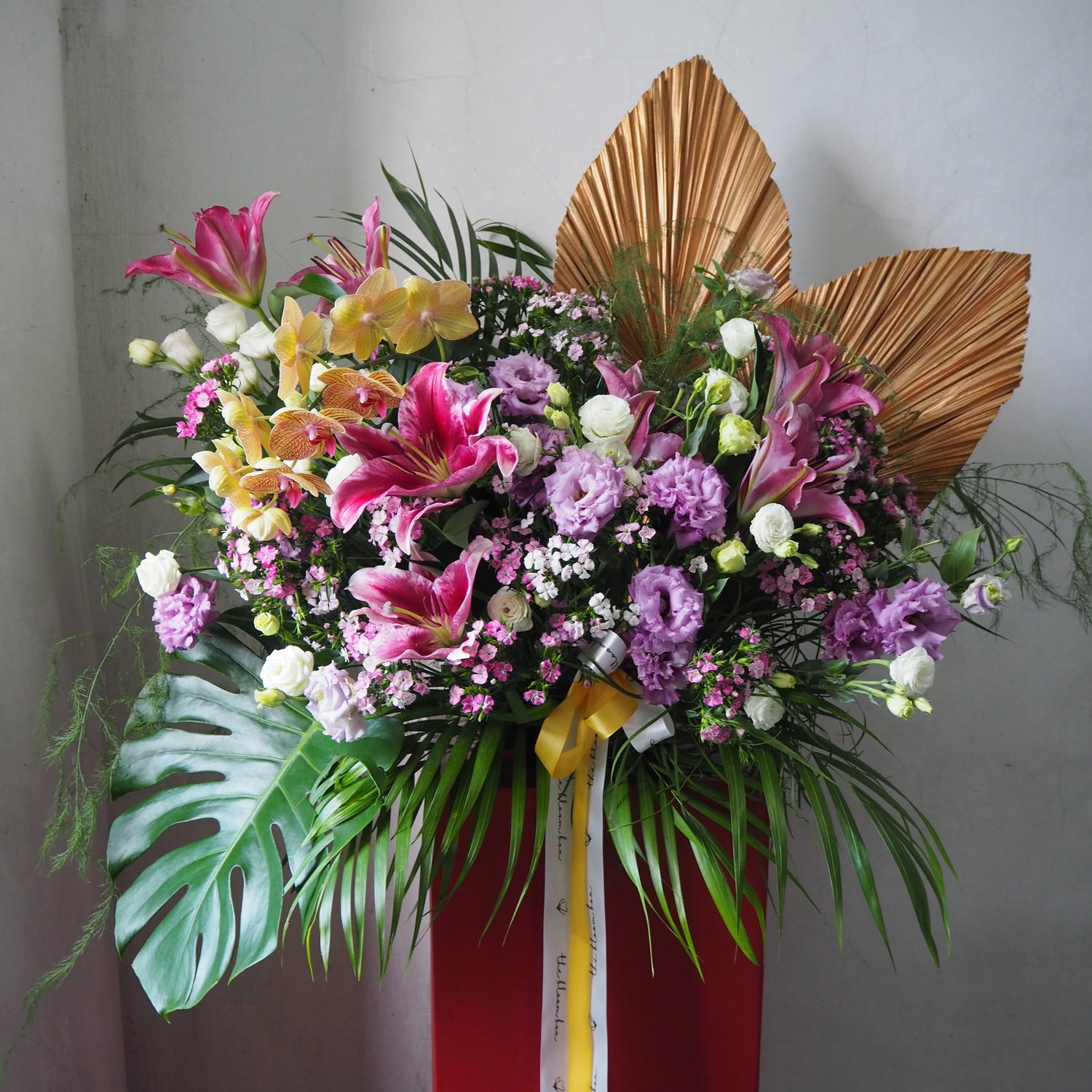 Colorful flower arrangement with a red base and gold leaves on a plain background