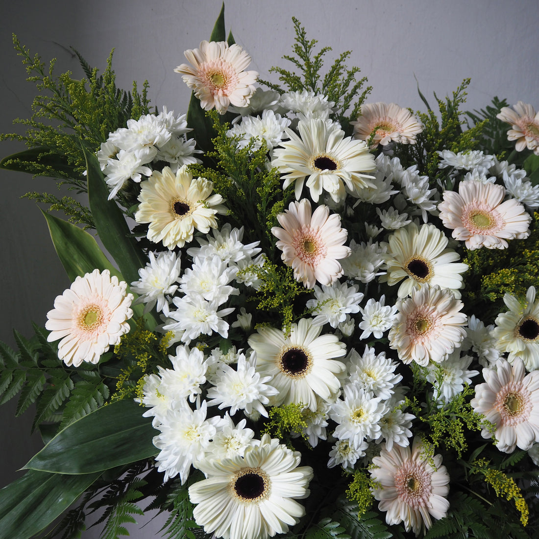 Bouquet of white and light pink flowers with greenery on a gray background