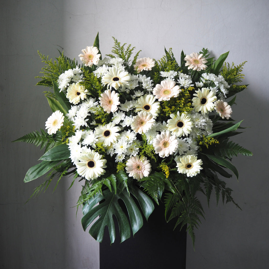Floral stand of white and green flowers on a gray background
