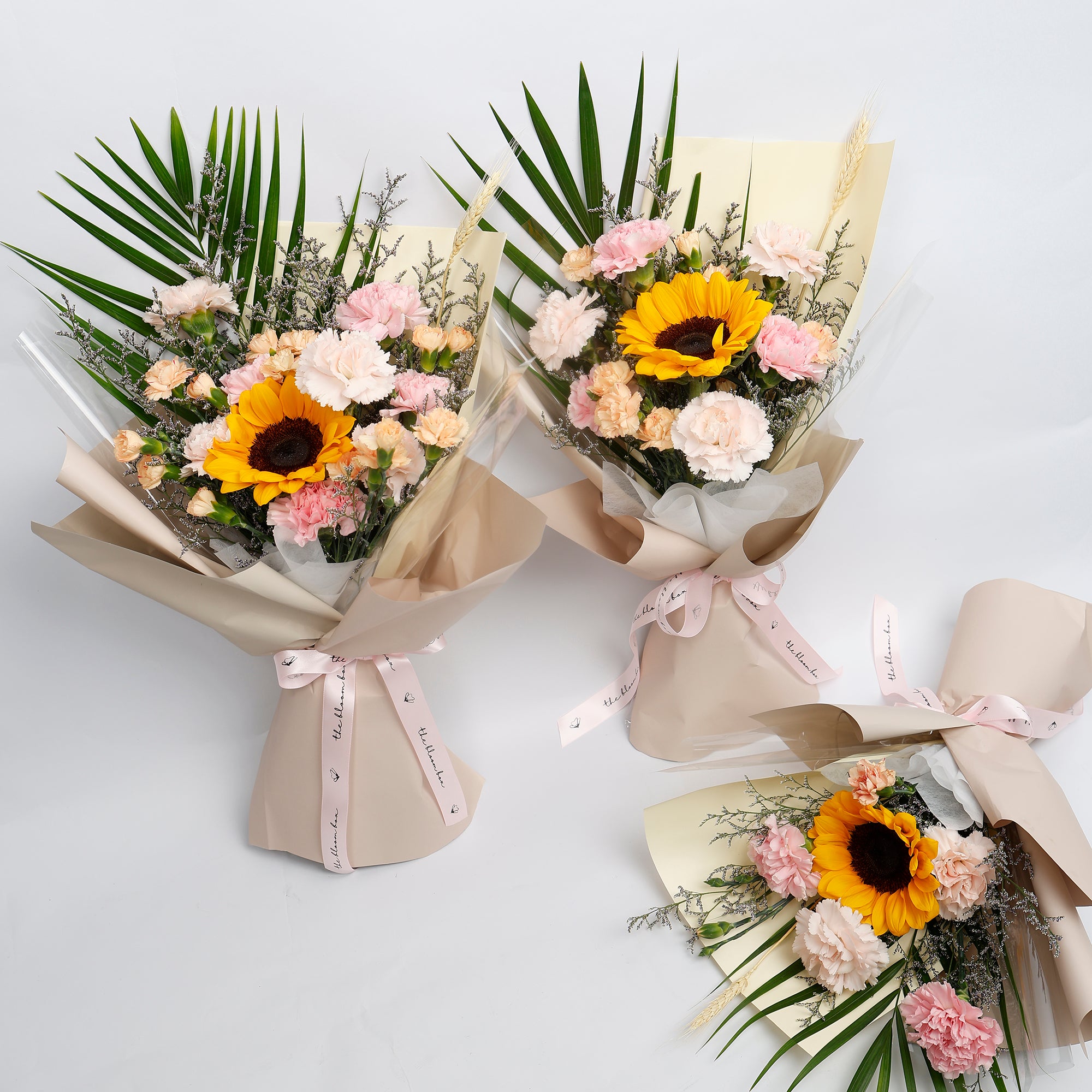 Three bouquets of flowers with sunflowers and pink flowers on a white background