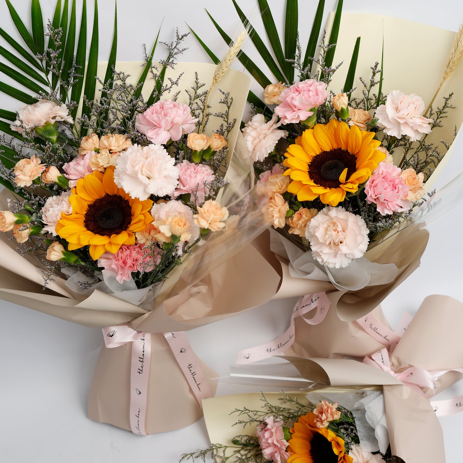 Two bouquets of flowers with sunflowers and pink carnations on a white background