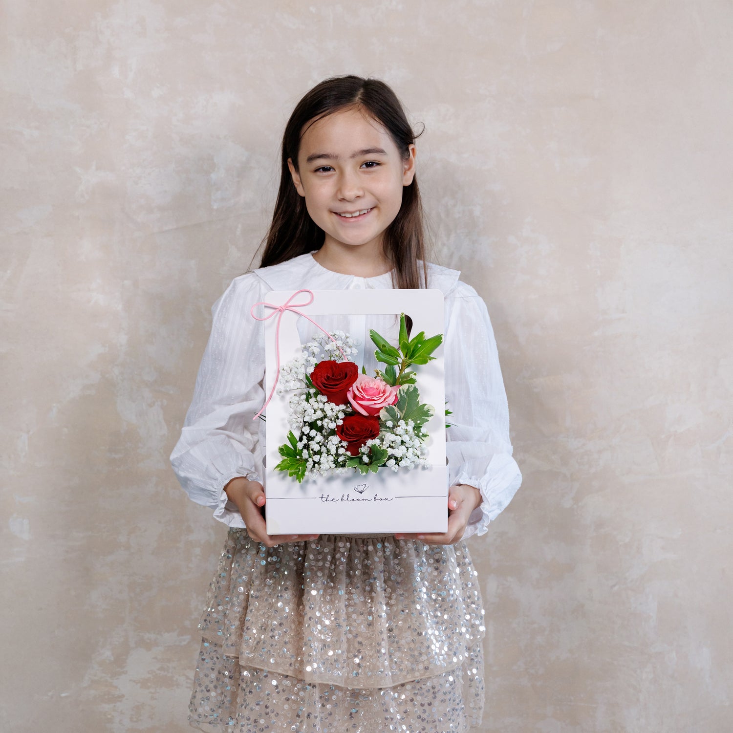 Young girl holding a bouquet of flowers against a plain background