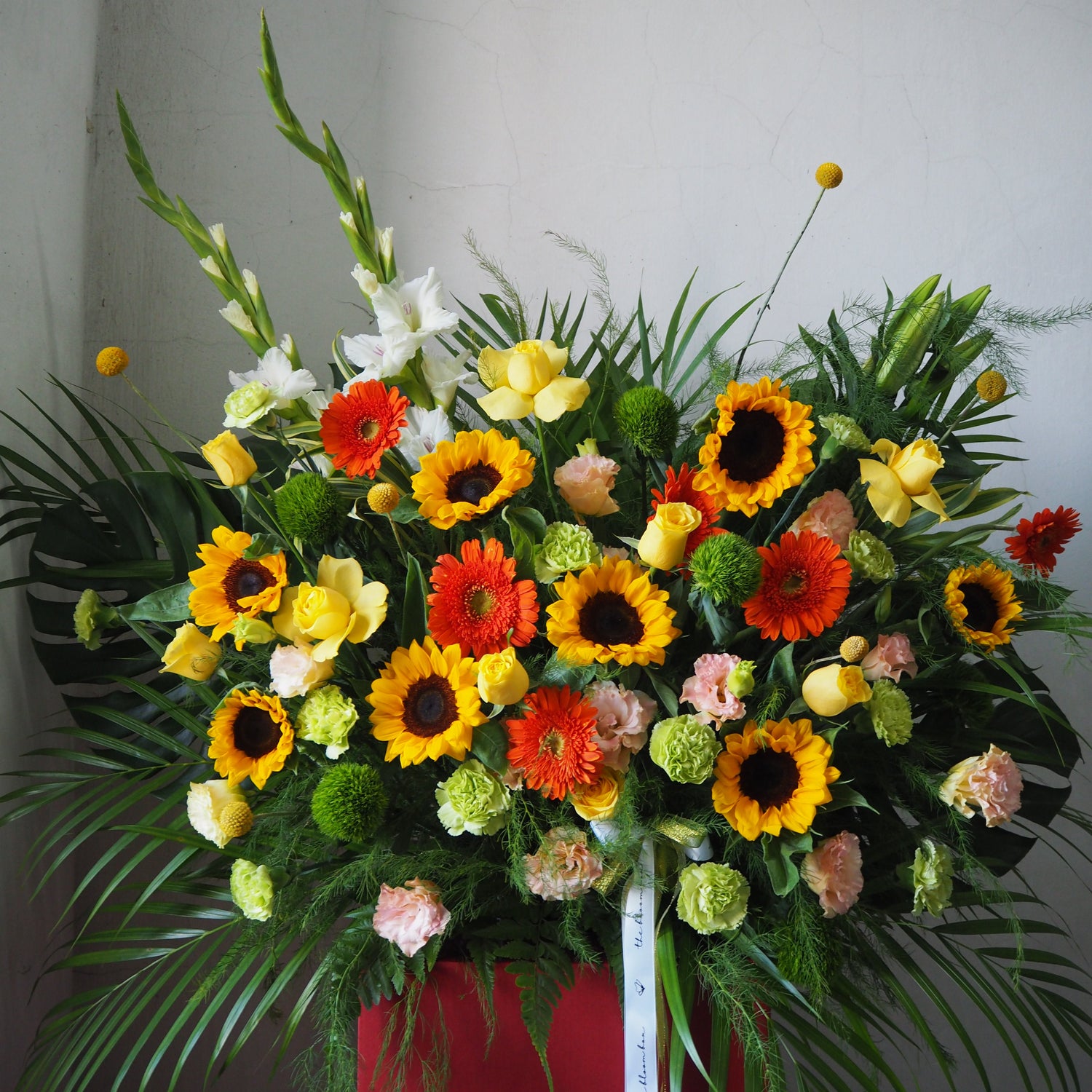 Colorful flower arrangement with sunflowers, roses, and other flowers on a plain background