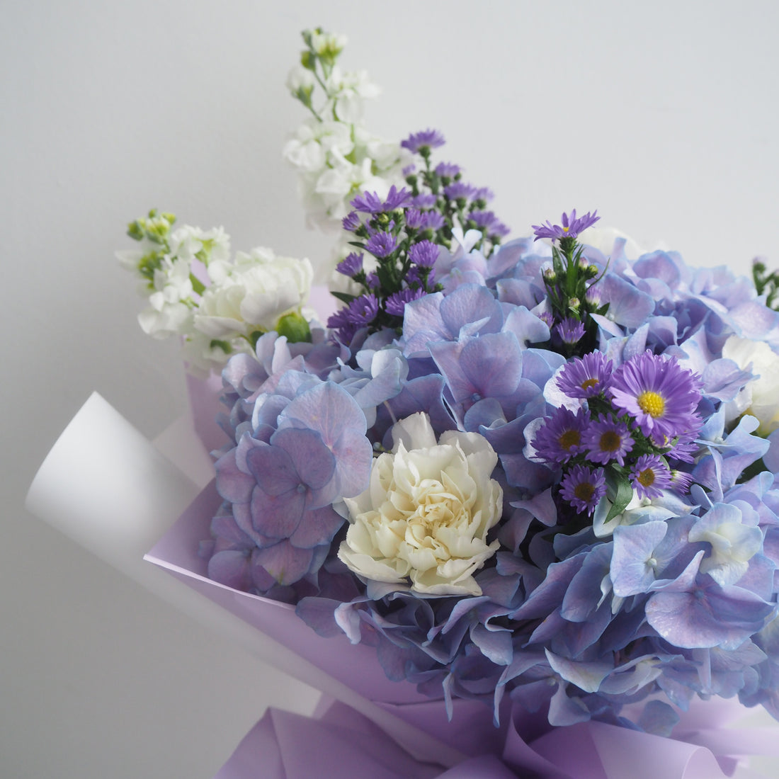 Wisteria bouquet wrapped in purple and white paper, ready for same-day delivery in Singapore